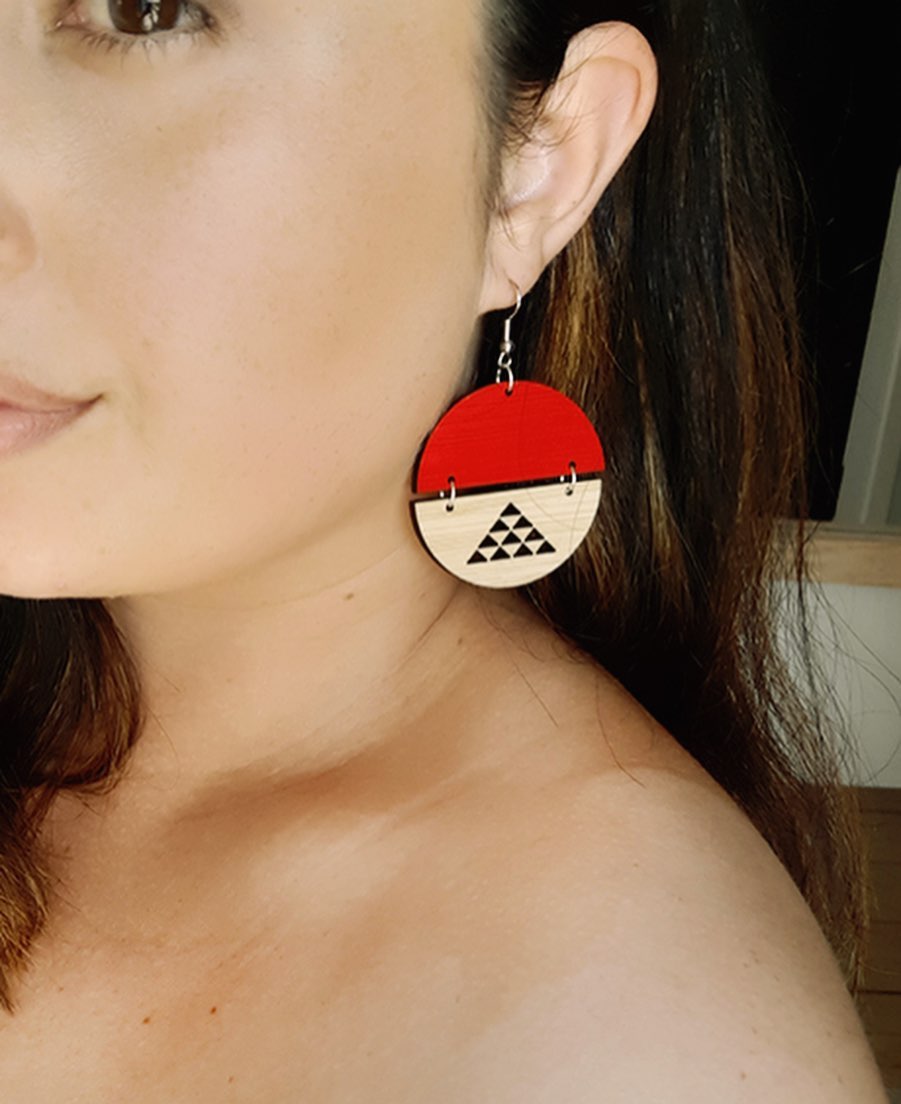 Woman wearing red maori design circle earrings